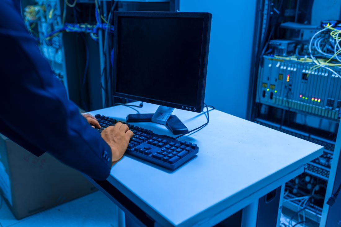 A technician working at a computer in a server room