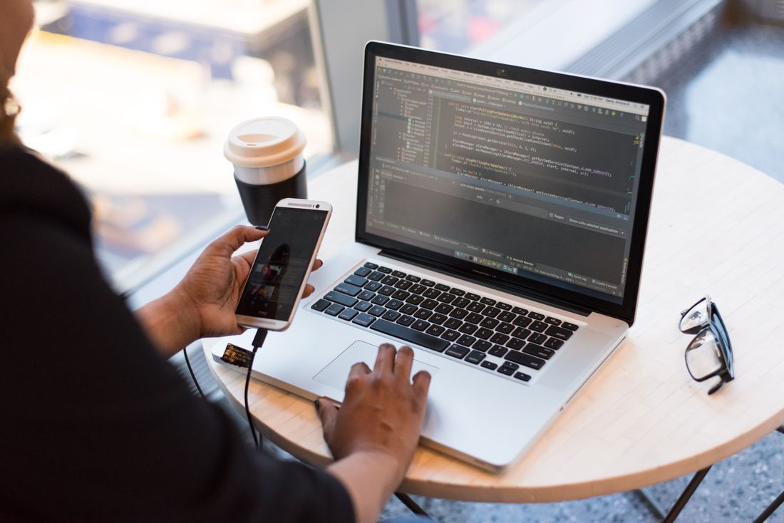 A developer testing a smartphone beside a laptop