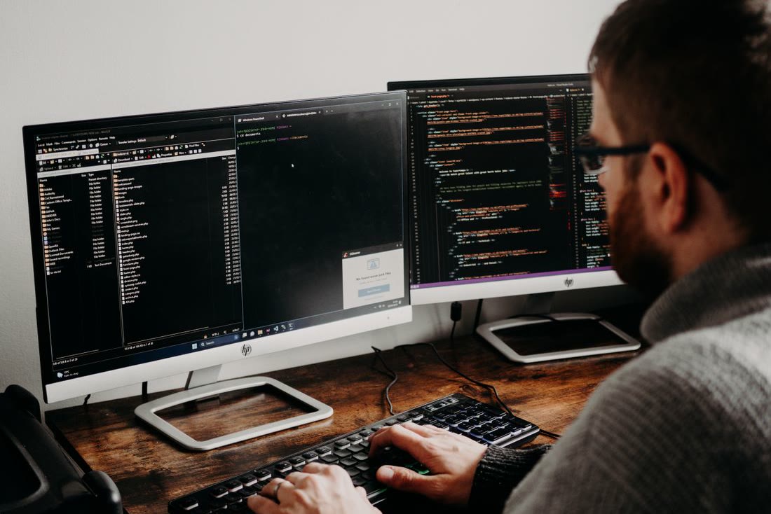 A developer writing code across two monitors