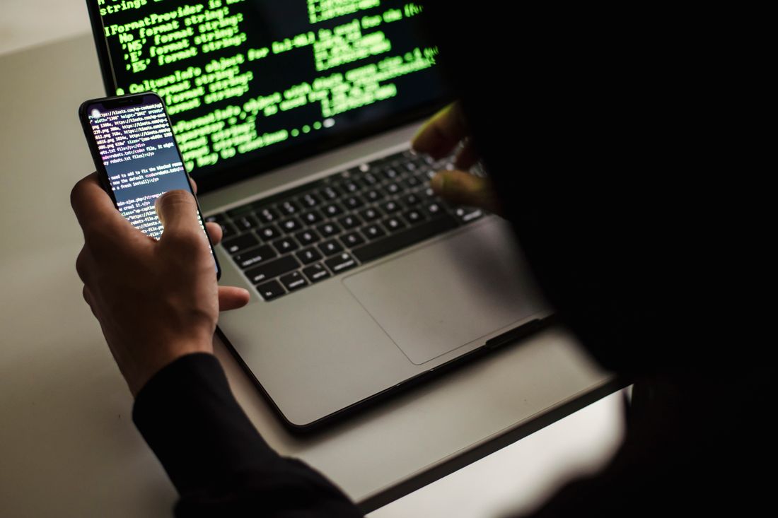 A developer working with code on a laptop and smartphone